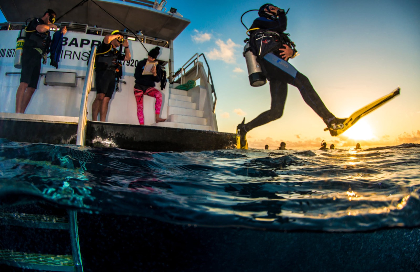 A diver taking a giant stride off the back of a dive boat