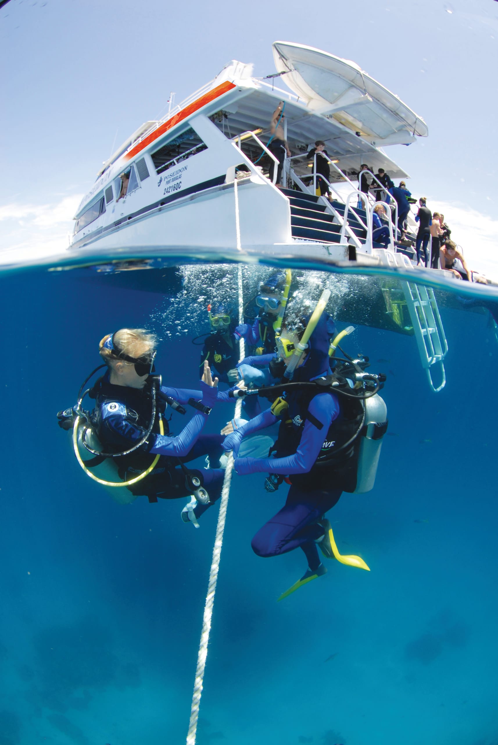 Divers entering the water from a dive boat on the reef